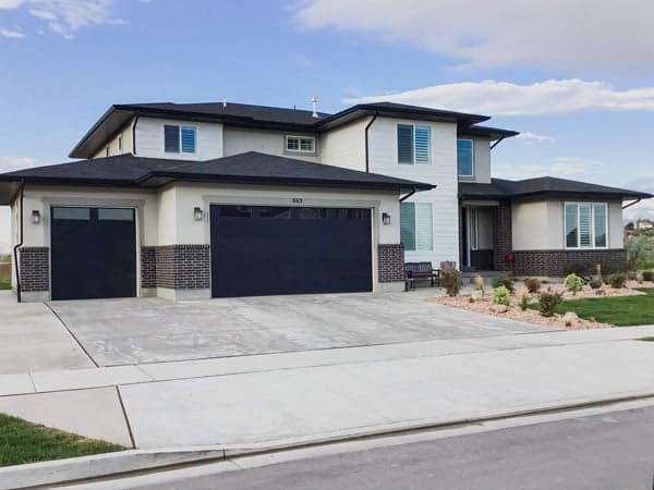 huge house with white sidings and blue garage doors