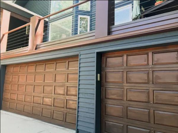 two brown garage doors and balcony railings above