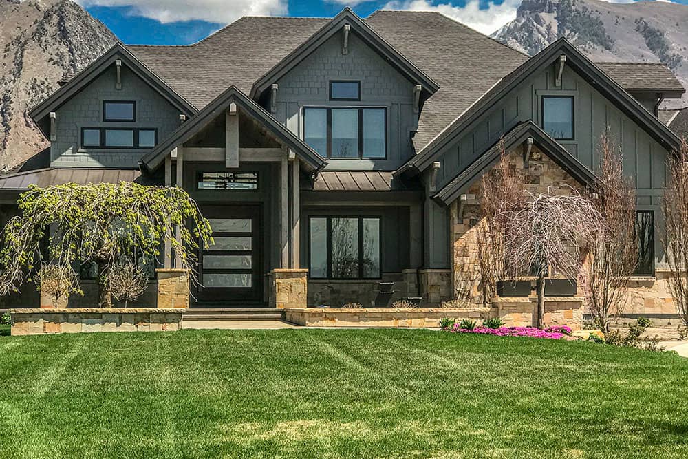 front view of a house with green lawn and mountains on the background